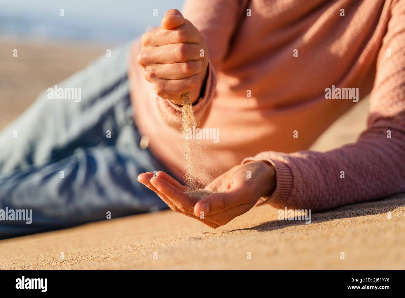 Sabbia che cade dal pugno chiuso della donna Foto Stock