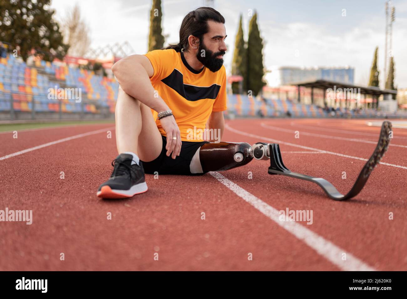 Atleta con gamba protesica seduta sulla pista da corsa Foto Stock