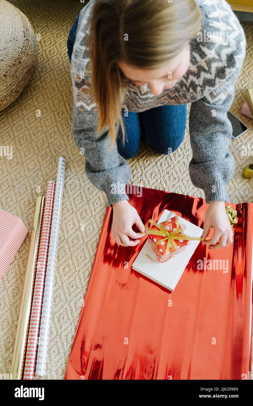 Donna che avvolge il regalo di Natale a casa Foto Stock