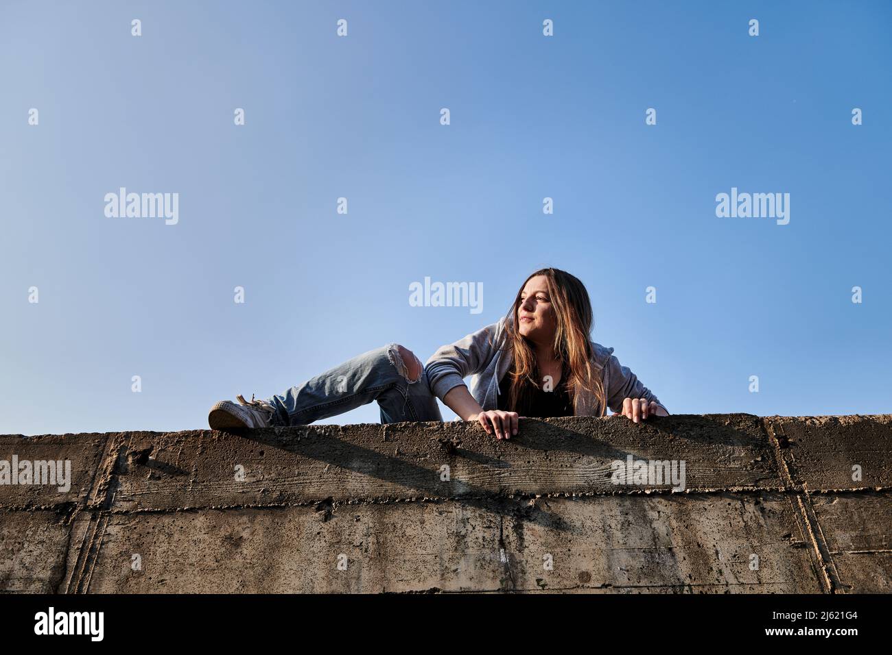 Giovane donna che si arrampica su un muro di cemento Foto Stock