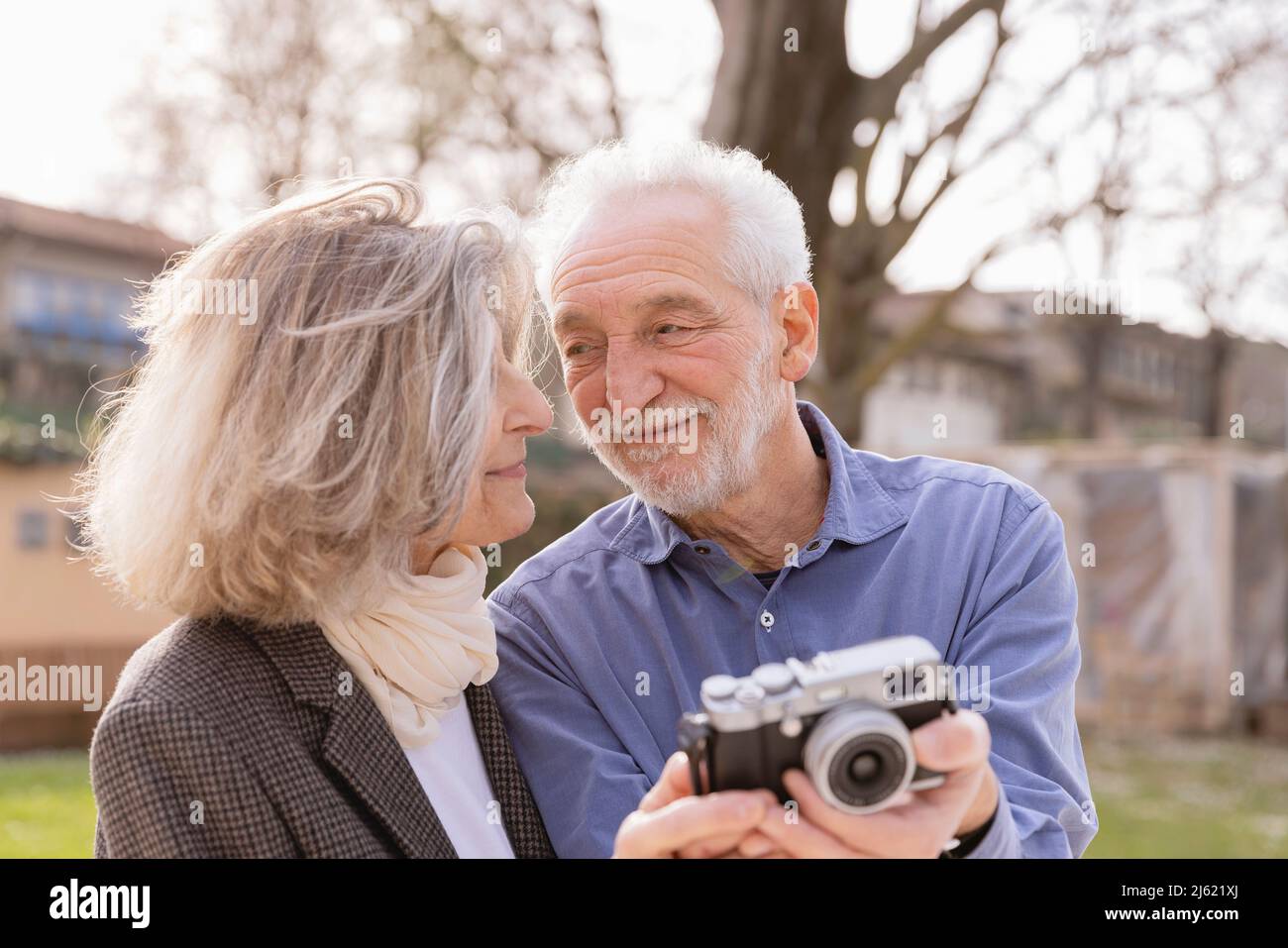 Coppia anziana felice con la macchina fotografica che si guarda l'un l'altro nella giornata di sole Foto Stock