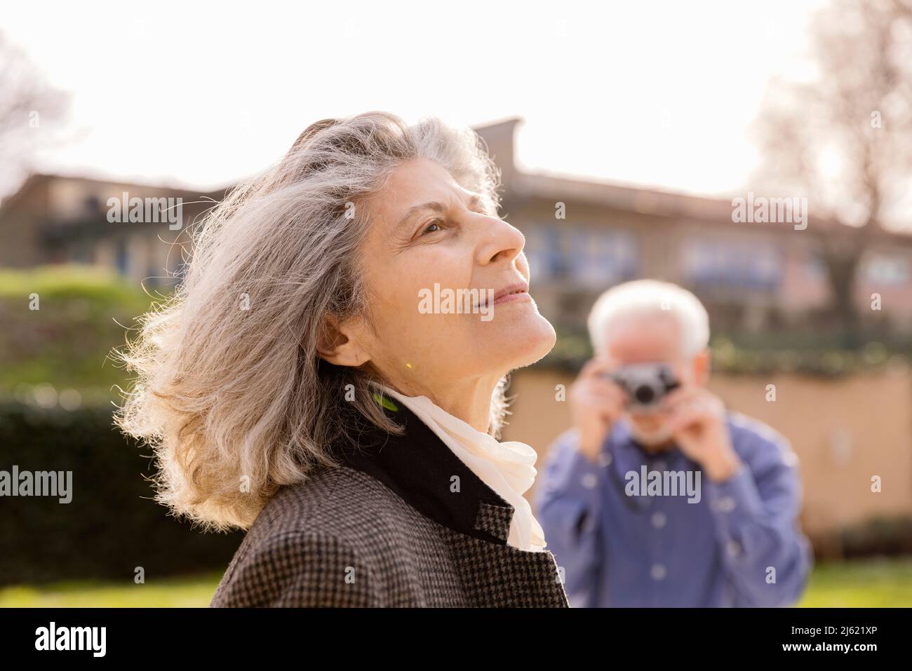 Uomo anziano che fotografa la donna in giornata di sole Foto Stock