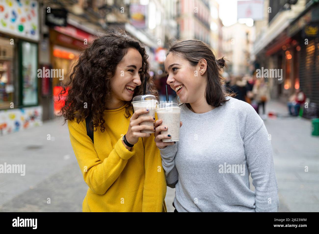 Amici felici godendo con tazze usa e getta di milkshakes Foto Stock
