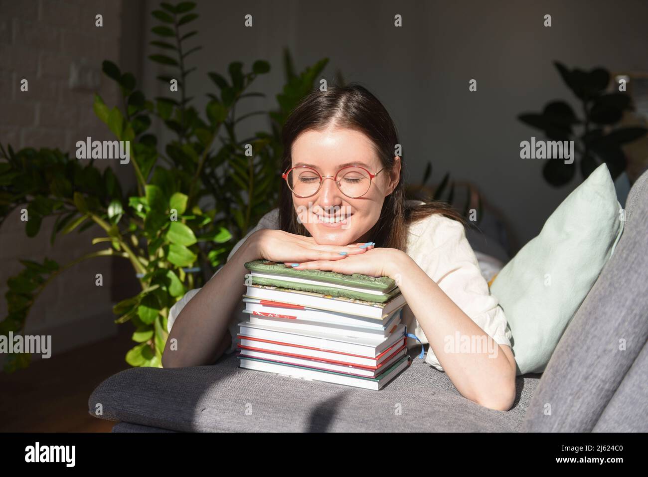 Donna felice con gli occhi chiusi appoggiandosi sui libri a casa Foto Stock