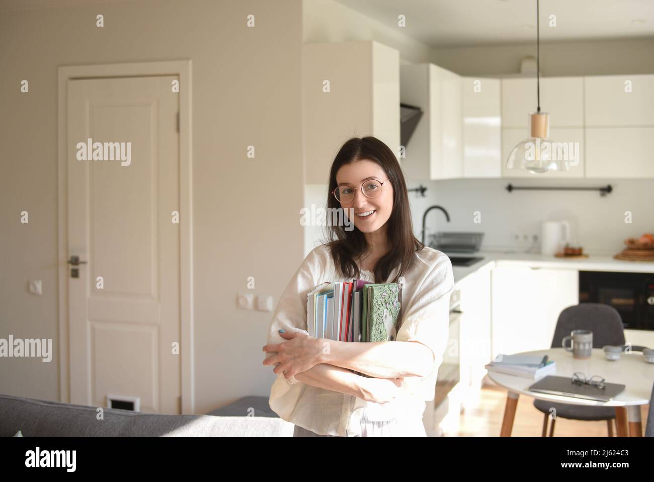 Donna felice con libri in piedi a casa Foto Stock