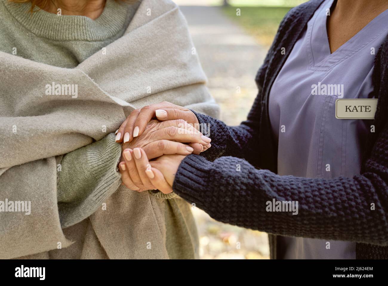 Caretaker tenere mani consolante donna anziana Foto Stock