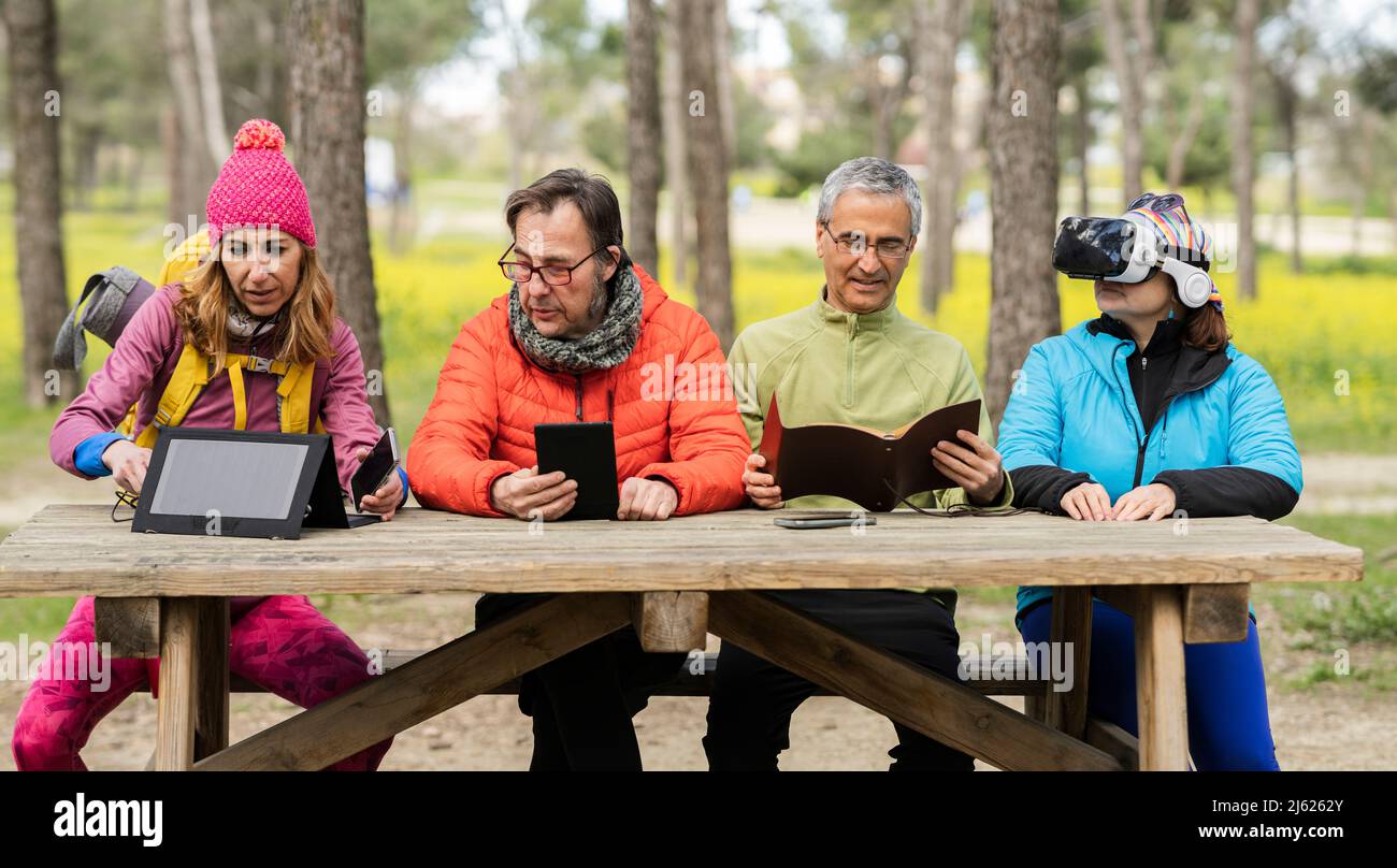 Uomini e donne maturi seduti al tavolo da picnic nella foresta Foto Stock