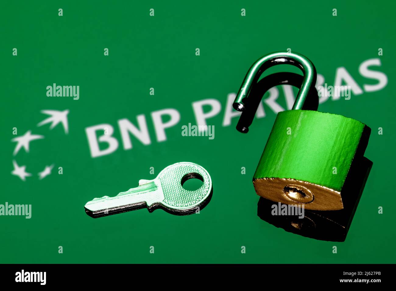 Un lucchetto di sicurezza aperto e chiave sullo sfondo del logo BNP Paribas Bank in riflessione speculare Foto Stock