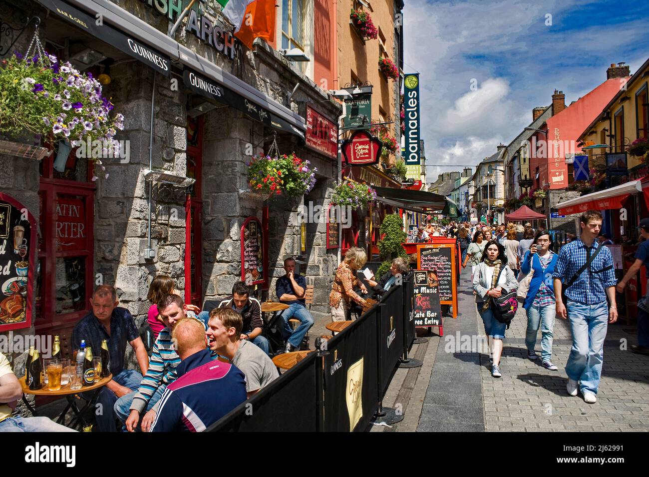 I turisti godono del sole nella strada principale di Galway City, Contea di Galway, Irlanda Foto Stock