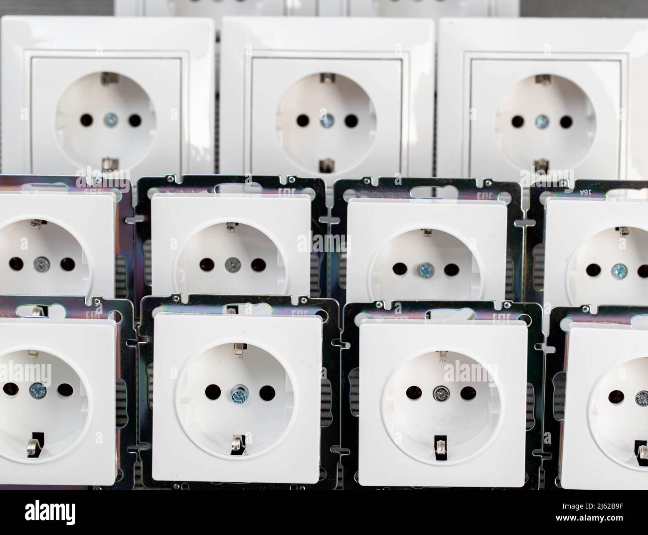 Molte prese elettriche moderne su sfondo grigio, primo piano. Aumento del prezzo dell'elettricità per kilowatt, con conseguente risparmio di elettricità Foto Stock