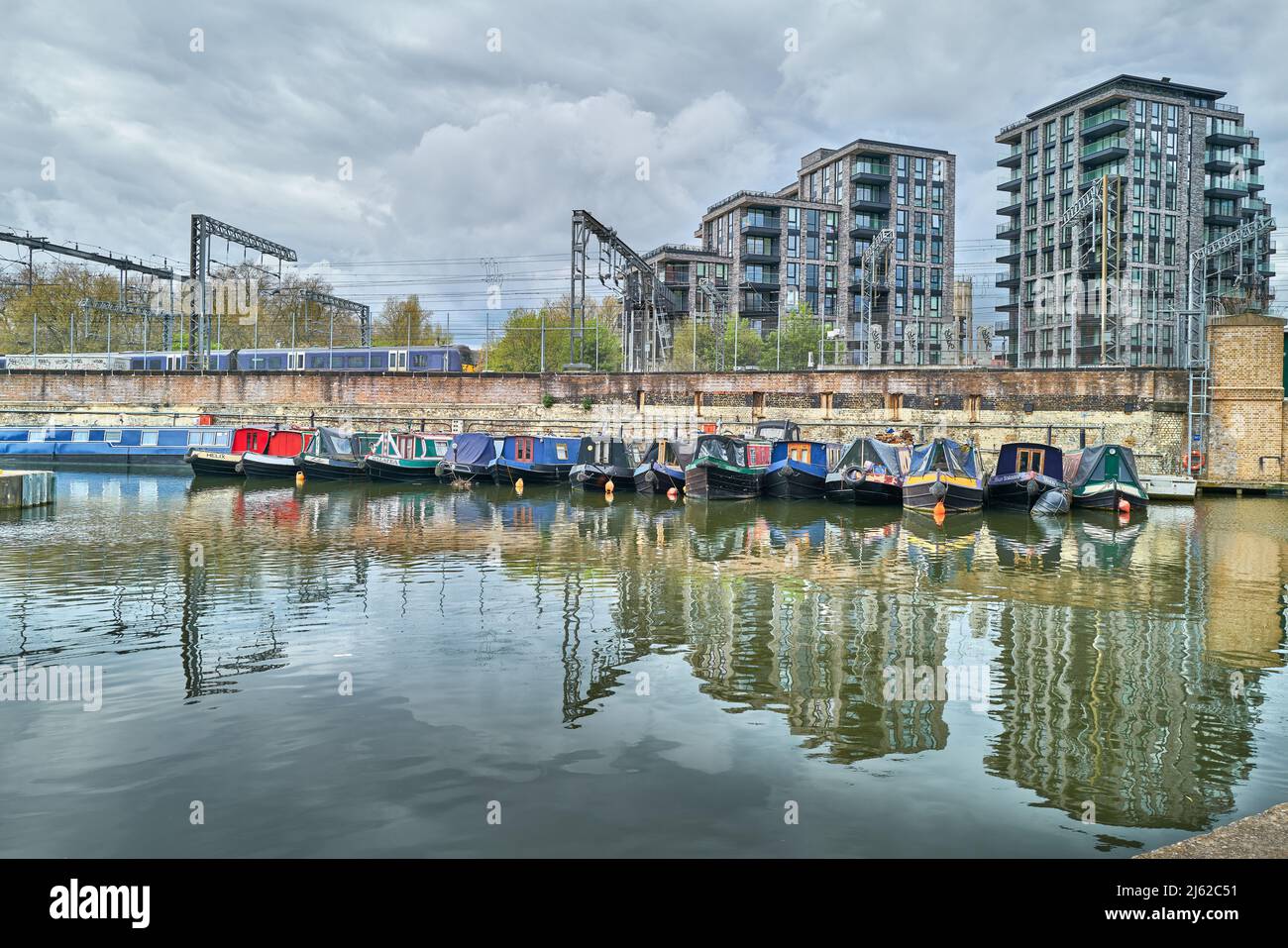 Le barche dei canali ormeggiano al bacino di St Pancras del canale Regent accanto alla linea ferroviaria della stazione ferroviaria di St Pancras, Londra, Inghilterra. Foto Stock