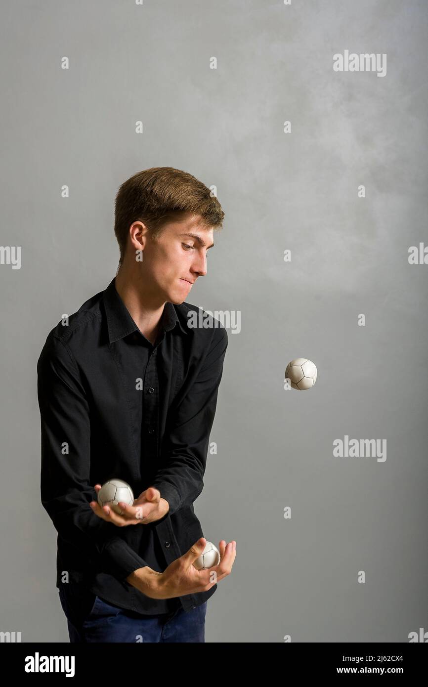 il ragazzo giocoliere si giocolca con tre palle Foto Stock