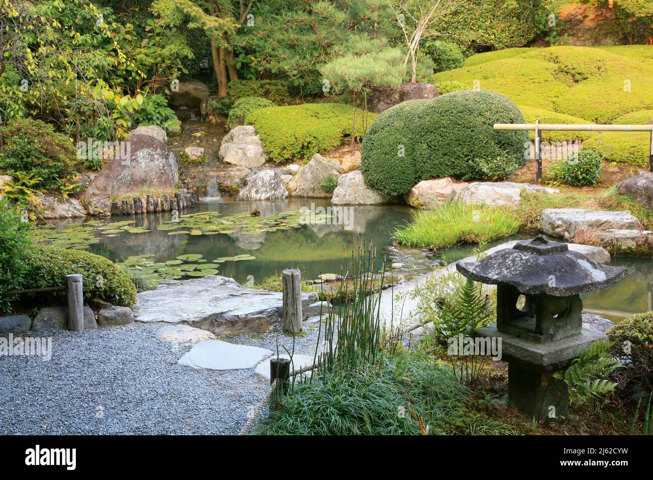 Un nuovo giardino laghetto o yoko-en di Taizo-in tempio con un flusso che cade intorno a rocce e azalee e si svuota in una piscina. Kyoto. Giappone Foto Stock