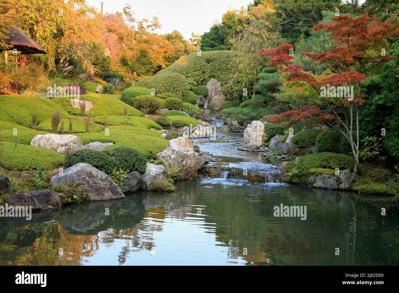 Un nuovo giardino laghetto o yoko-en di Taizo-in tempio con un flusso che cade intorno a rocce e azalee e si svuota in una piscina. Kyoto. Giappone Foto Stock