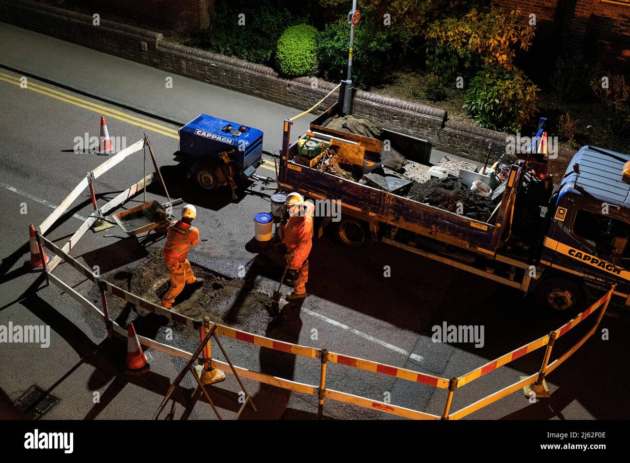 Lavori stradali notturni, riparando una copertura di botola rotta nella strada, in Hertfordshire, Regno Unito. Lavori eseguiti da fornitori Cappagh, per conto di Thames Water. Foto: David Levenson/Alamy Foto Stock