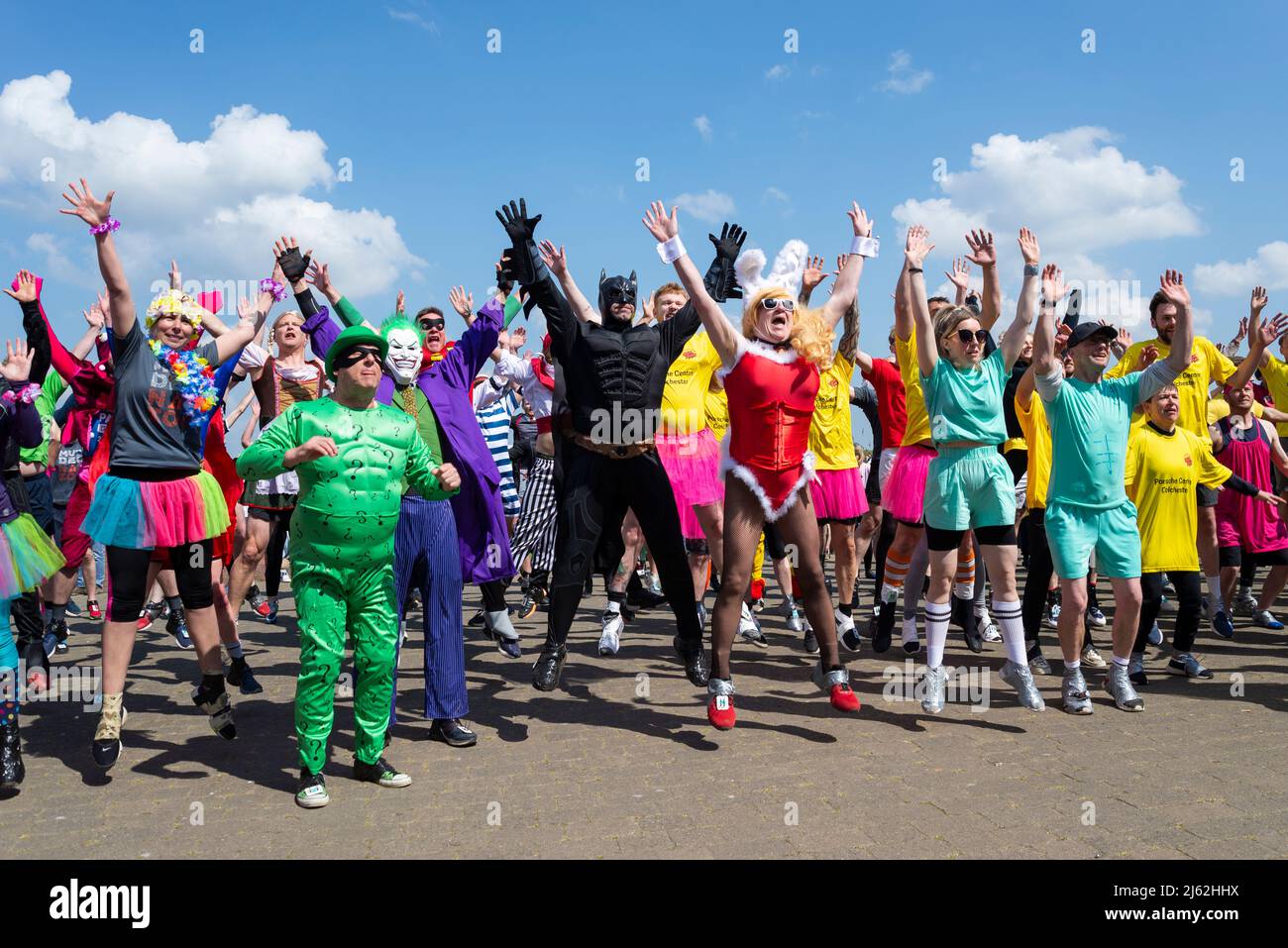 I concorrenti si riscaldano prima della Maldon Mud Race 2022, molti in costume. A Promenade Park, Maldon, Essex, Regno Unito Foto Stock