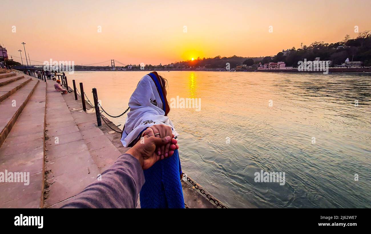giovane coppia che tiene le mani al tramonto a ganges banca del fiume da un angolo diverso immagine è preso a ganga riva del fiume rishikesh uttrakhand india. Foto Stock