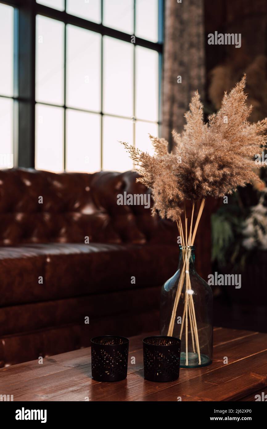 Vaso con fiori secchi si erge su un tavolo in legno all'interno Foto Stock