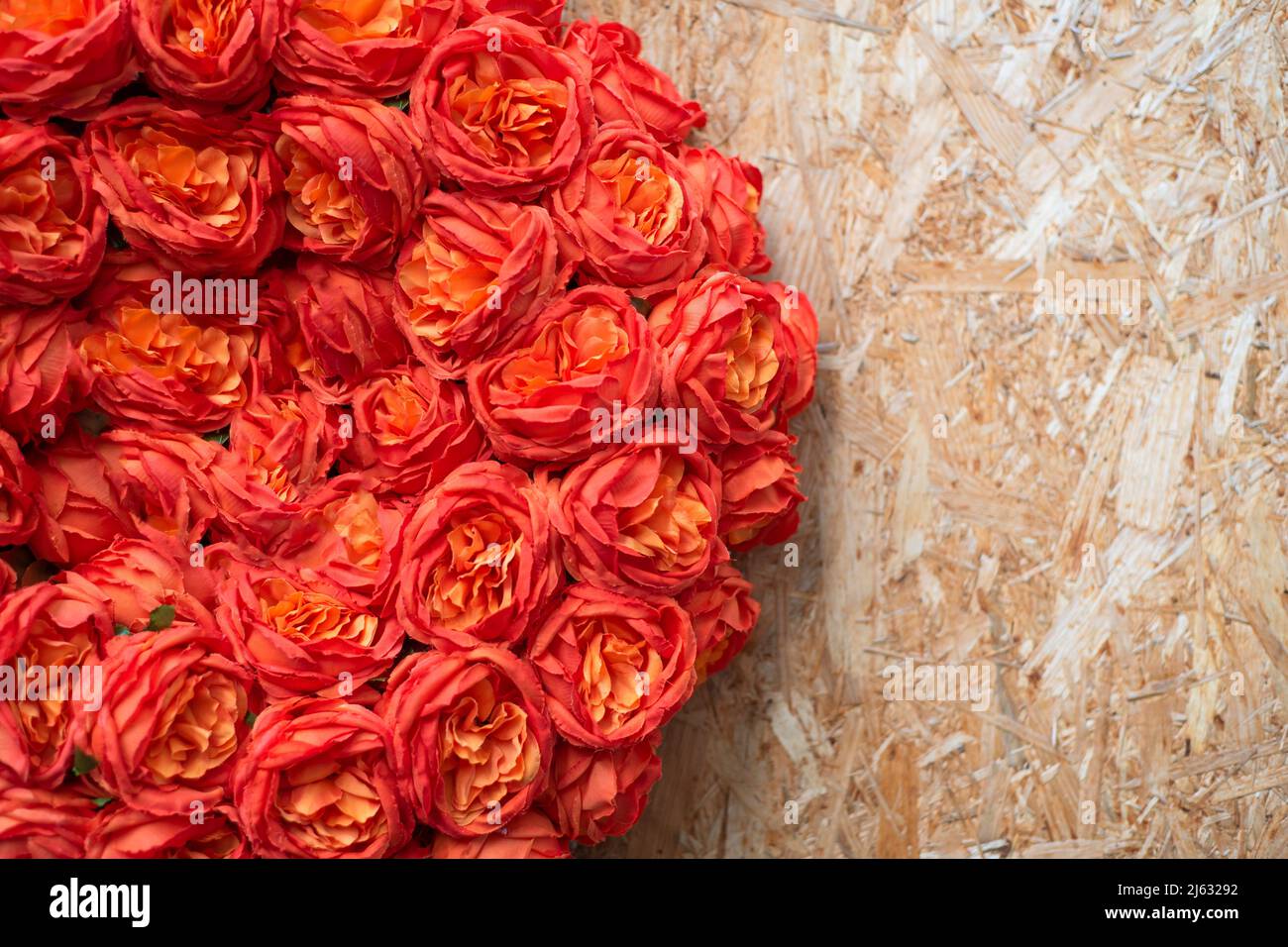 Texture fiori artificiali su legno compensato con spazio copia. Rose arancioni, sfondo floreale Foto Stock