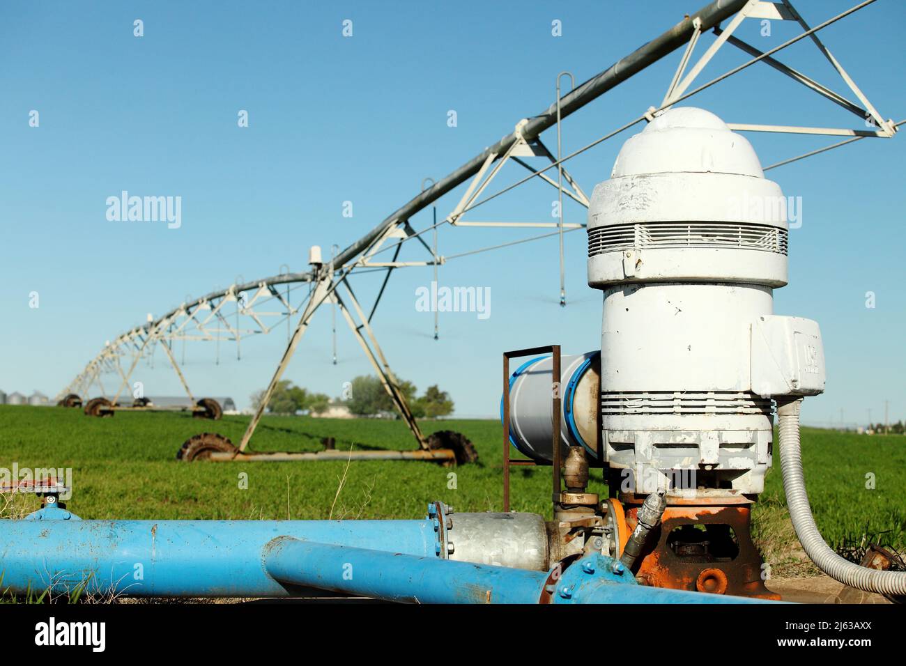 Una pompa di irrigazione agricola in un campo agricolo, utilizzata per consegnare le stoviglie ad un sistema di irrigazione a perno centrale che innaffia un campo di erba medica, Foto Stock