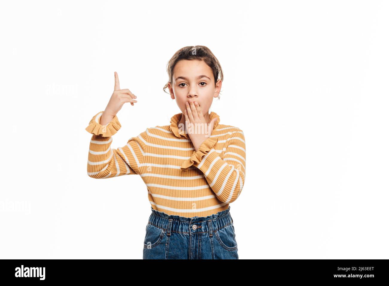 Ragazza che guarda la fotocamera con un'espressione scioccata sul suo volto mentre punta verso l'alto per mostrare qualcosa. Foto Stock