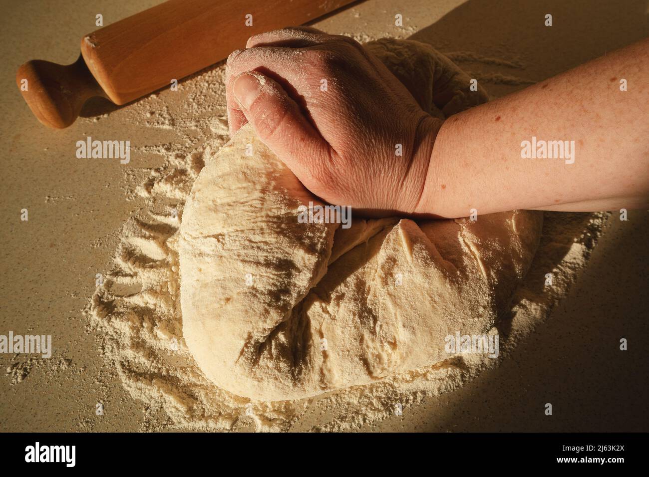 Preparare l'impasto per il pane, impastando l'impasto con le mani sul tavolo. Foto Stock
