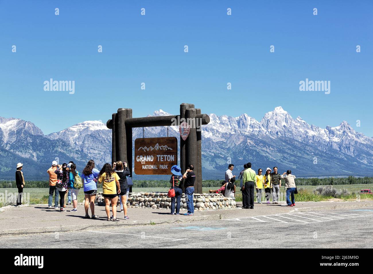 Un gruppo di turisti asiatici che scattano foto di fronte al cartello d'ingresso nel Parco Nazionale del Grand Teton. Foto Stock