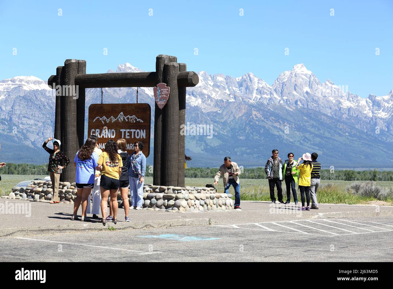 Un gruppo di turisti asiatici che scattano foto di fronte al cartello d'ingresso nel Parco Nazionale del Grand Teton. Foto Stock