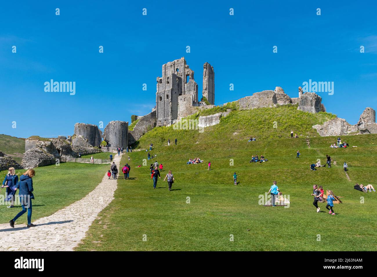 Corfe Castle a Dorset, Inghilterra, Regno Unito, un'attrazione turistica popolare impegnata con i visitatori in una soleggiata giornata di primavera Foto Stock