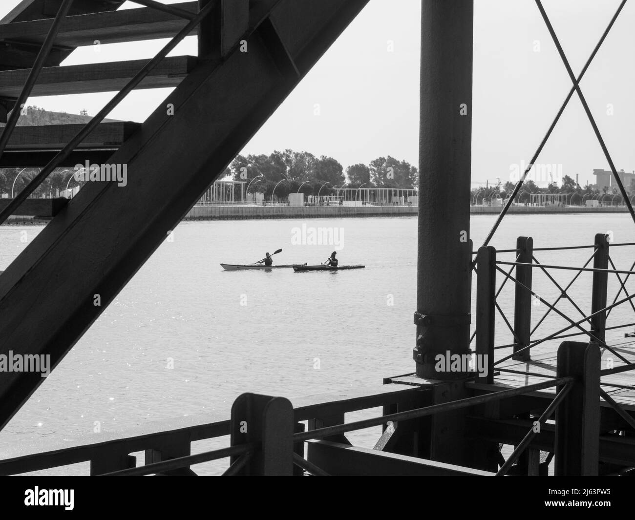 Due canoe che navigano nel fiume Huelva di fronte alla Muelle del Tinto, ex molo di carico e scarico di minerali. Foto Stock