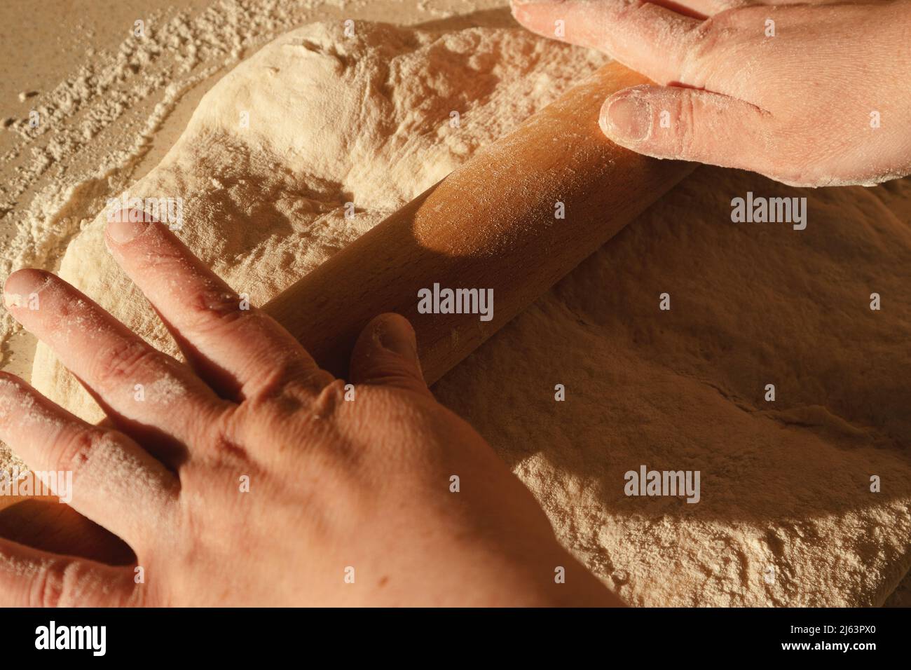 Preparare l'impasto per il pane, impastare l'impasto con un matterello sul tavolo. Foto Stock