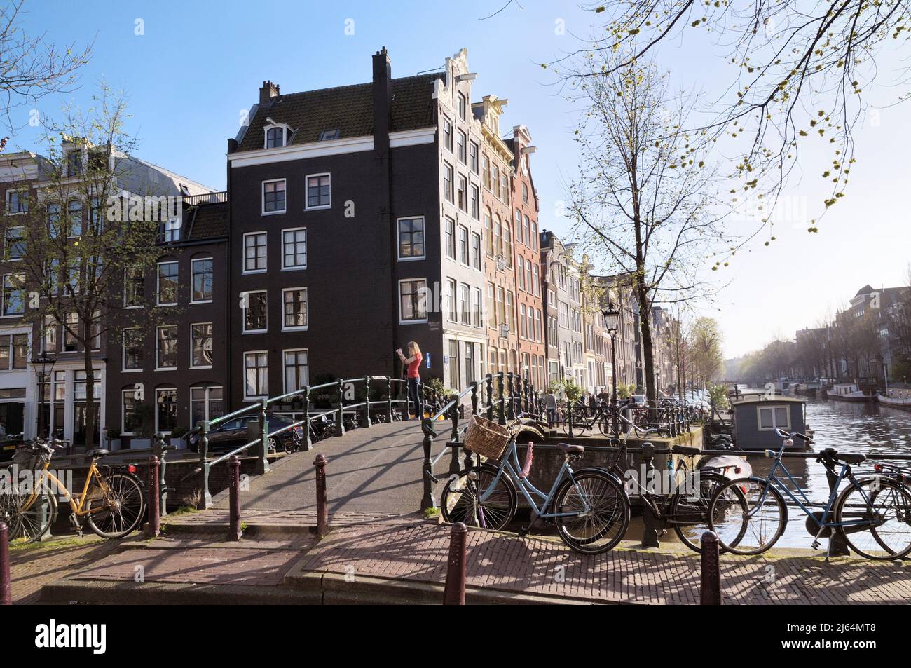Giovane donna che scatta una foto su un ponte all'angolo tra Brouwersgracht e Herengracht Canal, Jordaan, Amsterdam, Olanda settentrionale, Paesi Bassi, Europa Foto Stock
