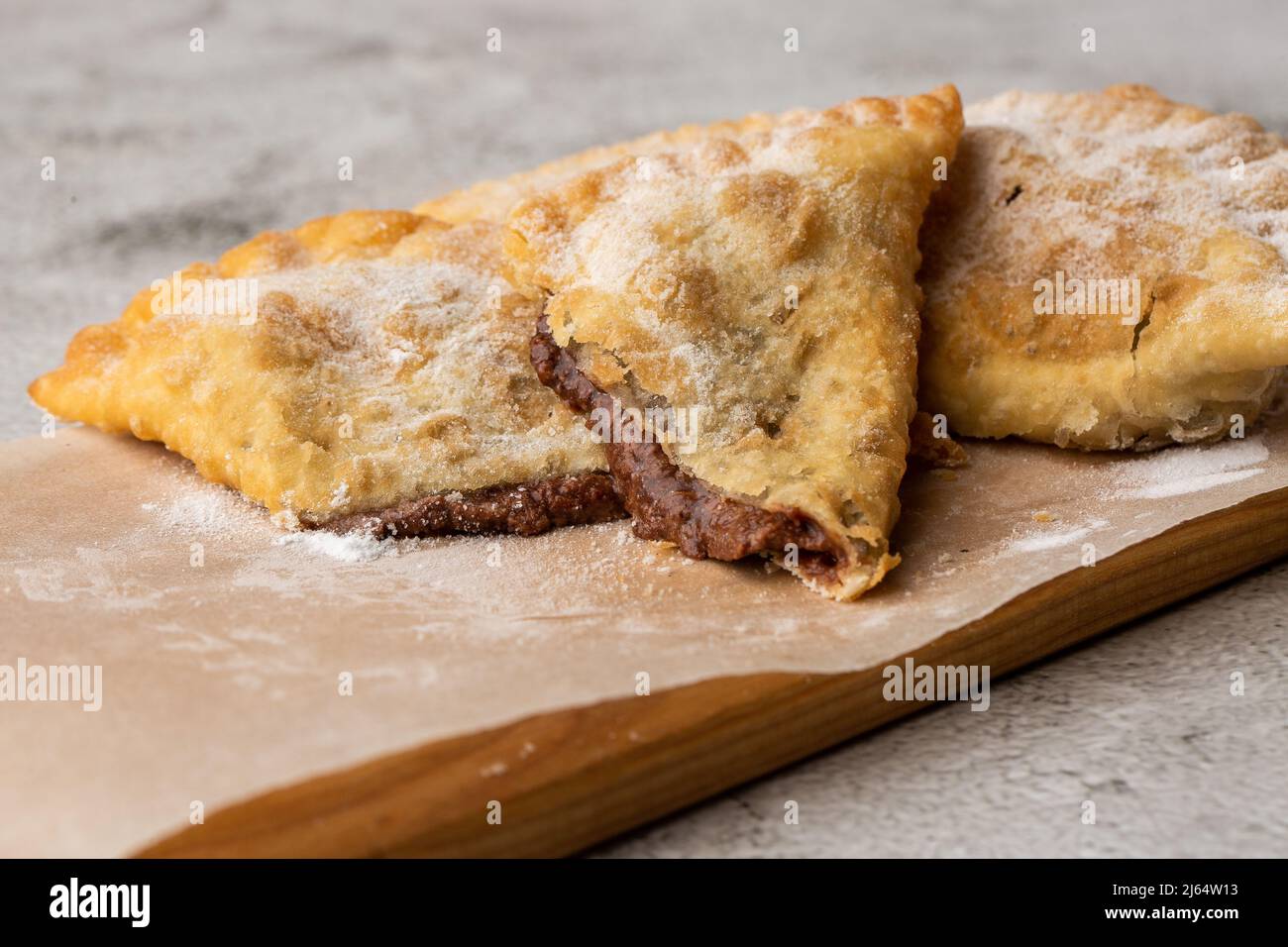 Cucina uzbeka orientale Tatar, formaggio dolce su un asse di legno. Cheburek - torta fritta con cioccolato Foto Stock
