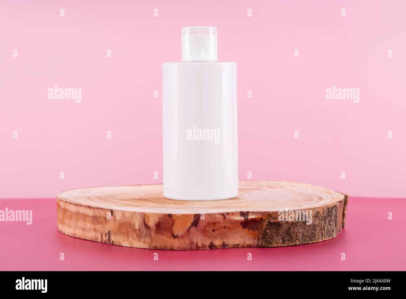 Detersivo, ammorbidente o sapone liquido sul podio rotondo in legno. Presentazione del mockup detergente su sfondo rosa. Liquido sanitario domestico per Foto Stock