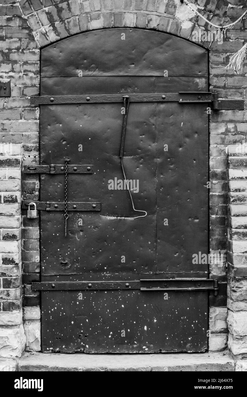 Una vecchia porta con serratura e catena, una vecchia vetrata in mattoni rossi pareti con alcuni lavori in muratura fatto su di loro in una vecchia area industriale di Toronto ora Foto Stock