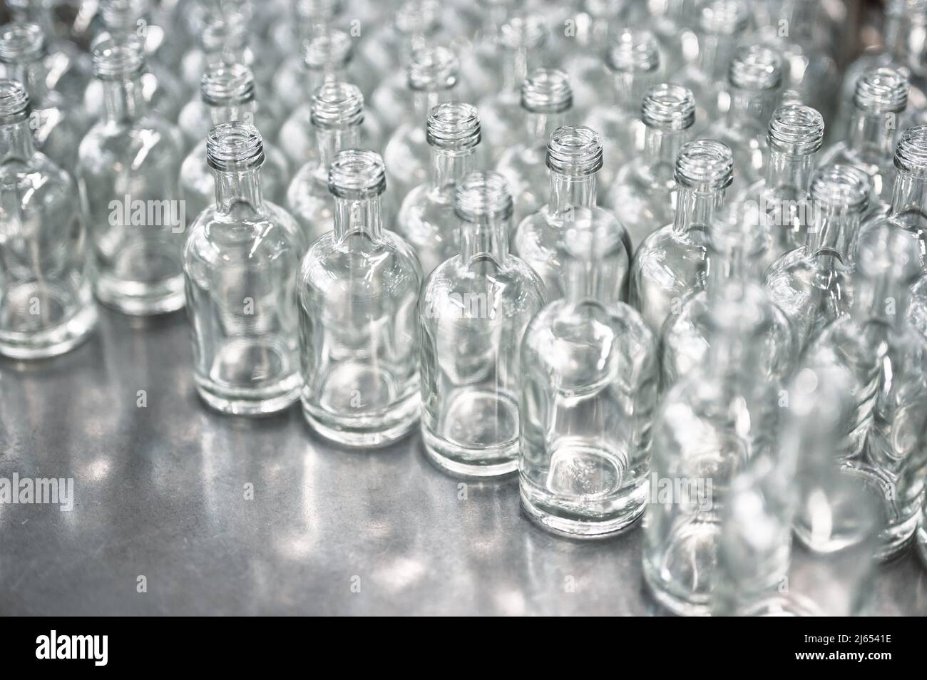 Linee di bottiglie di vetro vuote per bevande di vodka in officina Foto Stock