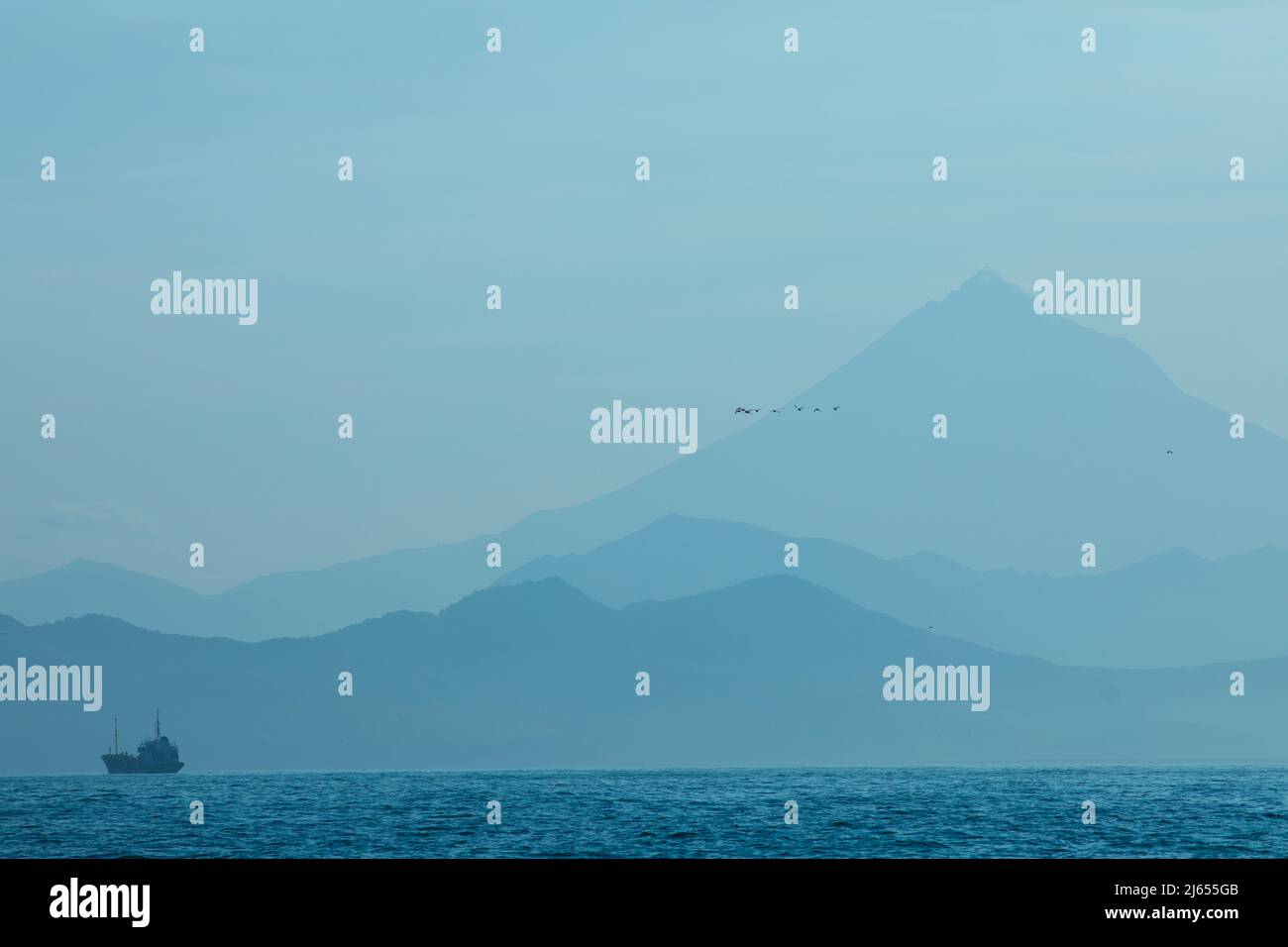 Montagne blu e mare paesaggio naturale sfondo con nave Foto Stock