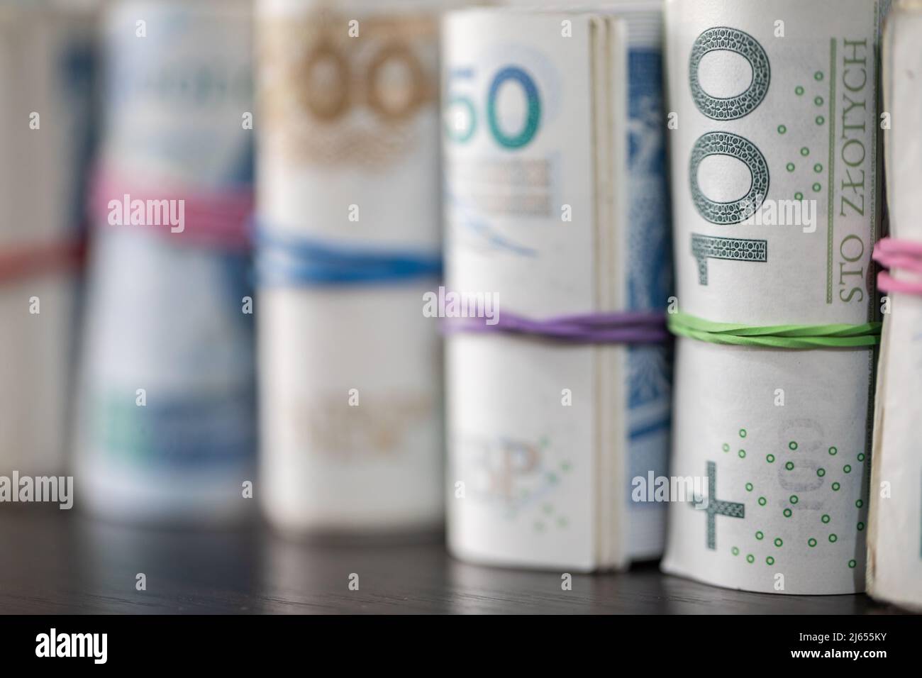 Sul tavolo sono presenti banconote polacche arrotolate in fila e legate con un nastro di gomma. Foto Stock
