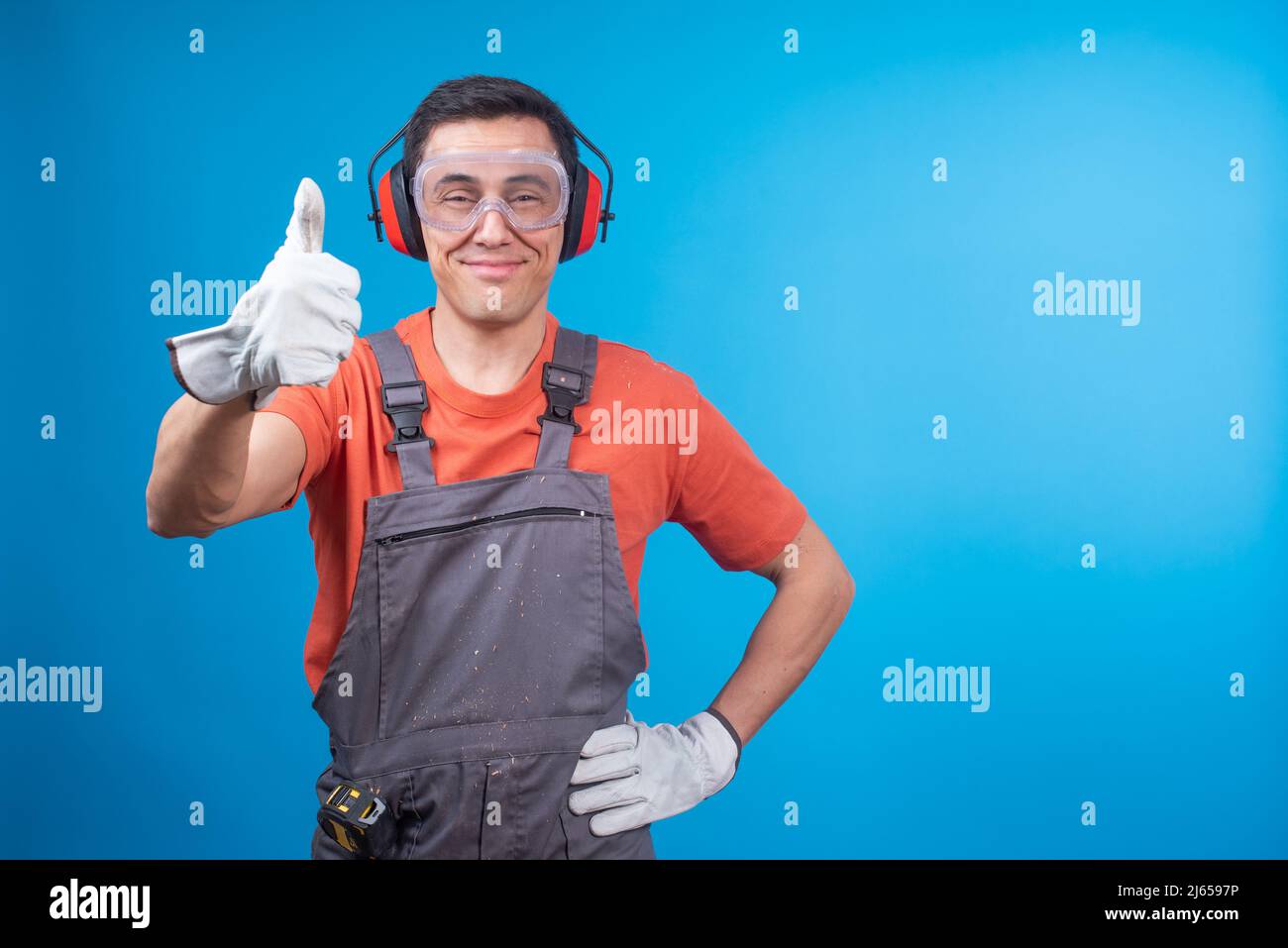 Orgoglioso falegname maschio gesturando il pollice su un sorridente Foto Stock