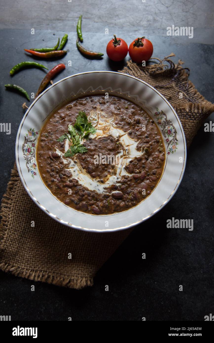 Dal makhni o dal makhani è una ricetta indiana del nord che utilizza lenticchie nere e fagioli rossi serviti in una ciotola su sfondo scuro. Vista dall'alto. Foto Stock