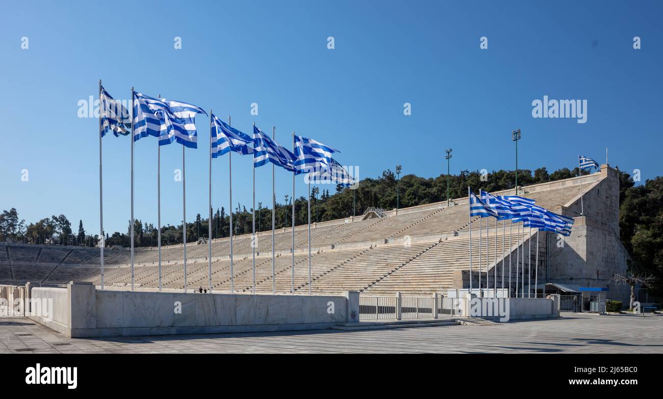 Atene, Grecia. Lo Stadio Panatenaico o Kallimarmarmaro. Antica arena atletica in marmo. Bandiere greche sui flagpoli che ondano in una giornata di sole, backg cielo blu Foto Stock