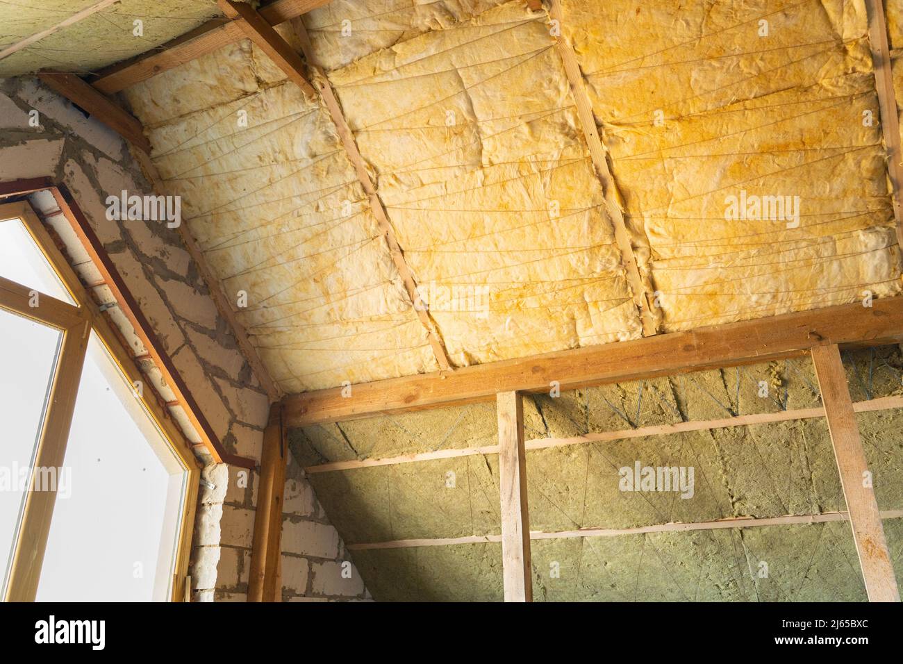 Isolamento del tetto in due strati di lana minerale e di lana di vetro si sovrappongono Foto Stock