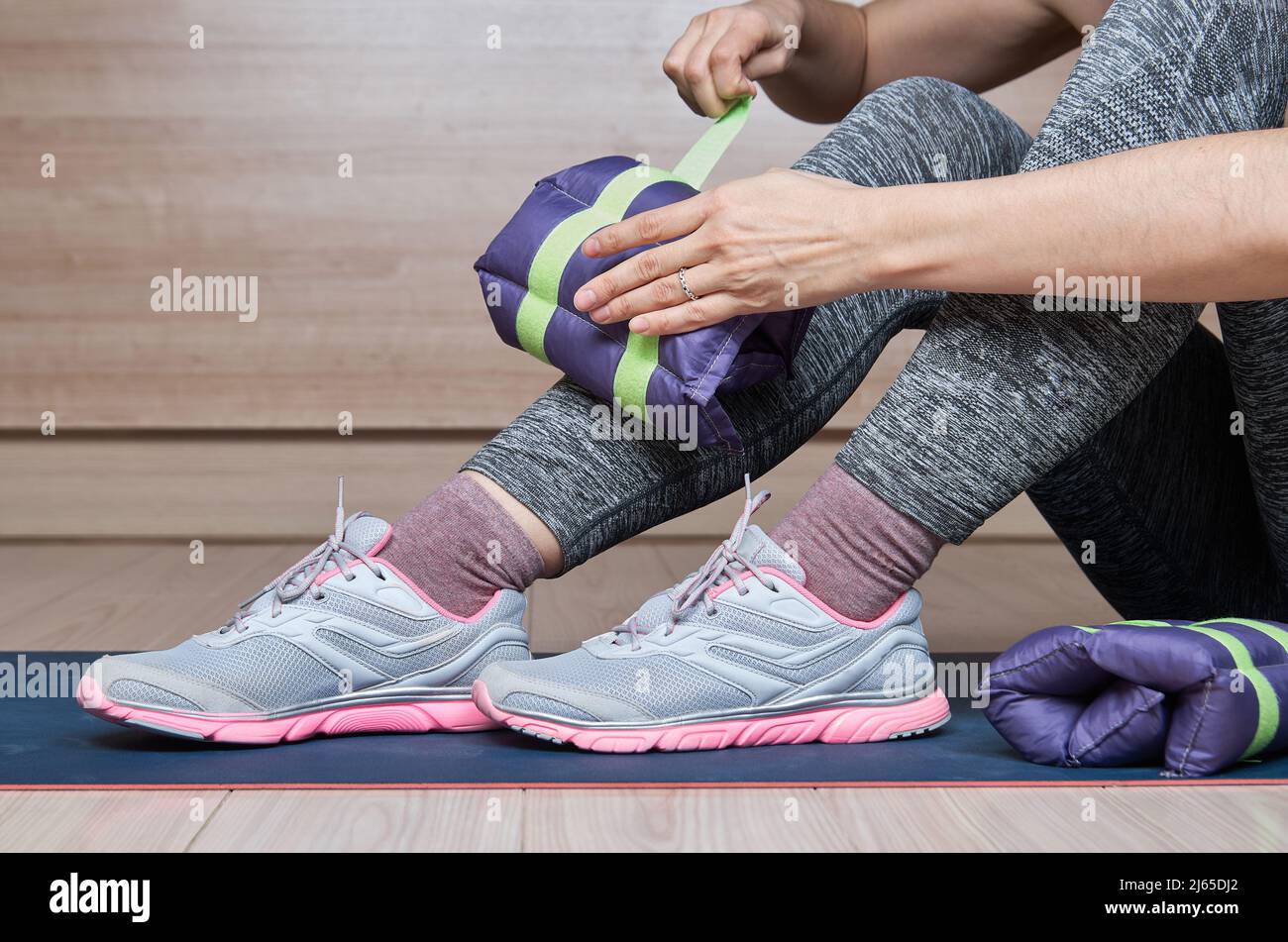 Donna in palestra mettendo pesi alla caviglia. Foto Stock