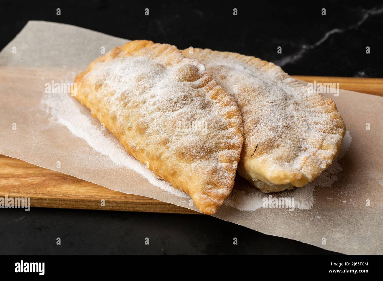Cucina uzbeka orientale Tatar, formaggio dolce su un asse di legno. Cheburek - torta fritta con cioccolato Foto Stock