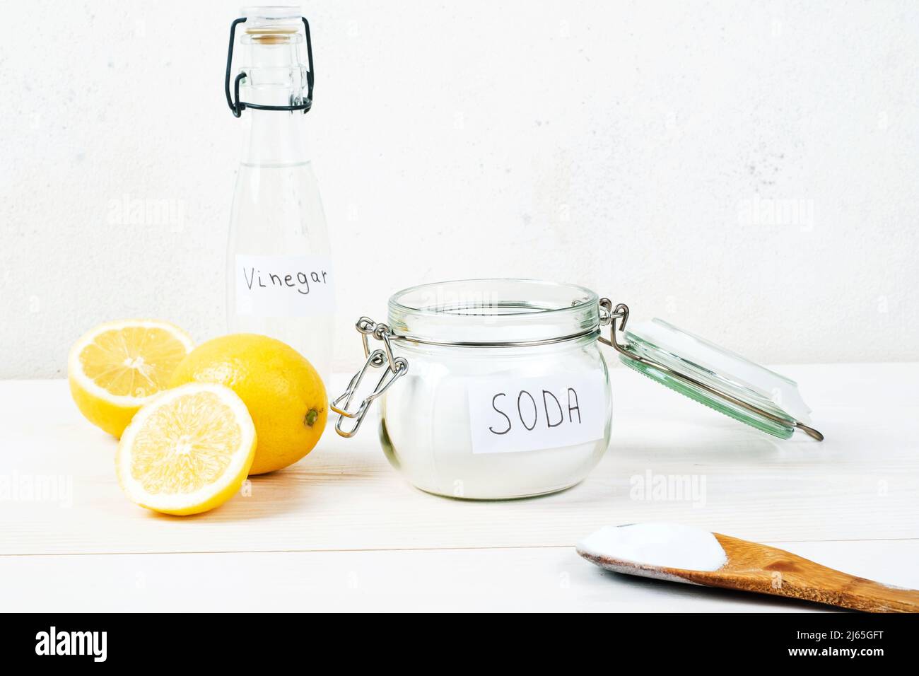 Bicarbonato di sodio in vaso, aceto, limone, cucchiaio di legno su sfondo bianco. Il concetto di rimozione delle macchie sui vestiti. Foto di alta qualità Foto Stock