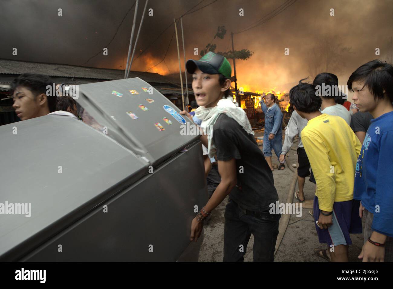 Gli uomini che trasportano un elettrodomestico come incidente di fuoco brucia un quartiere denso a Penjaringan, Giacarta Nord, Jakarta, Indonesia. Foto Stock