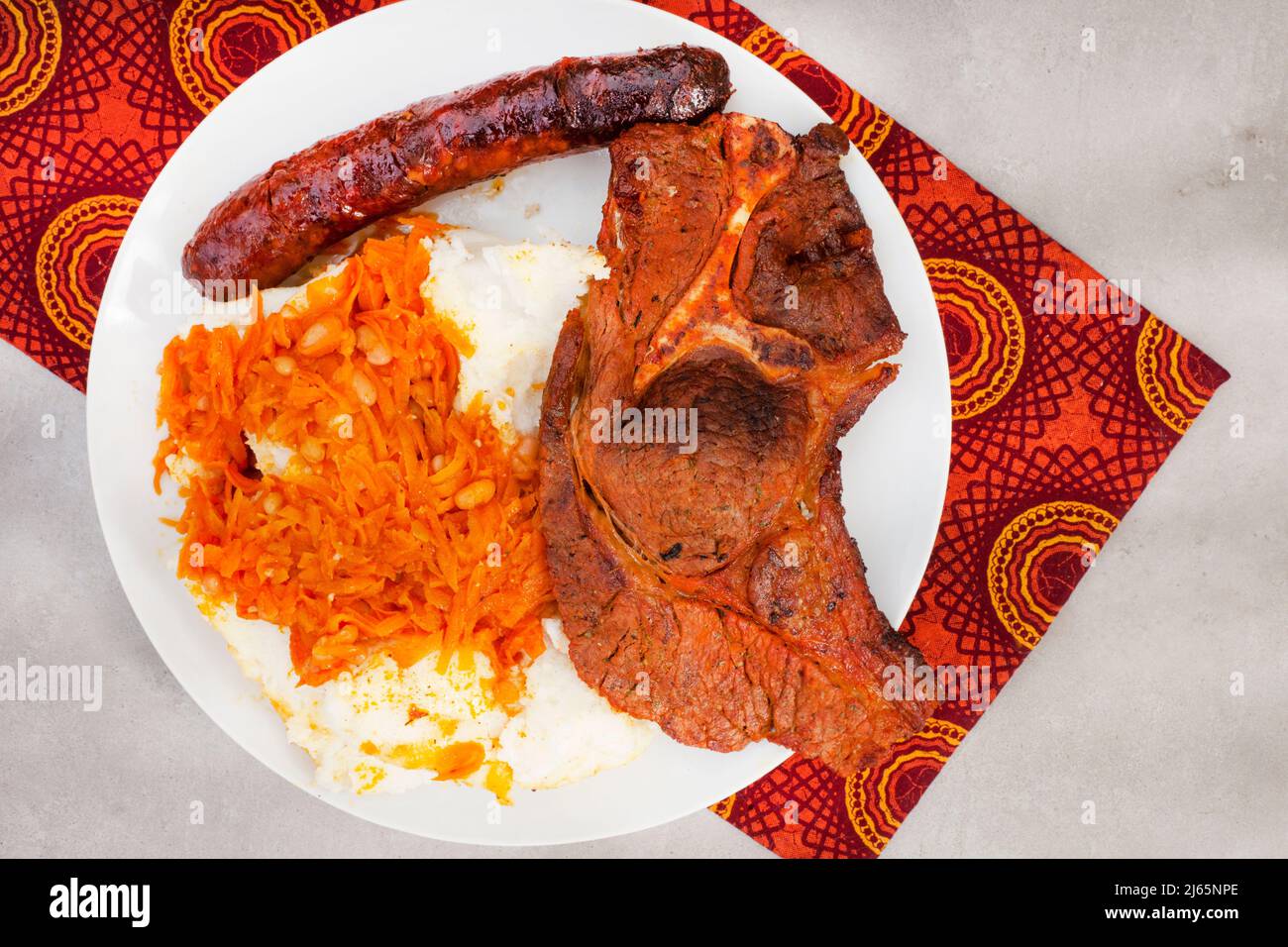 Piatto di Braai tradizionale sudafricano o Shisa nyama, carne cotta a fiamma libera e contorno tradizionale di pap e chakalaka. Foto Stock