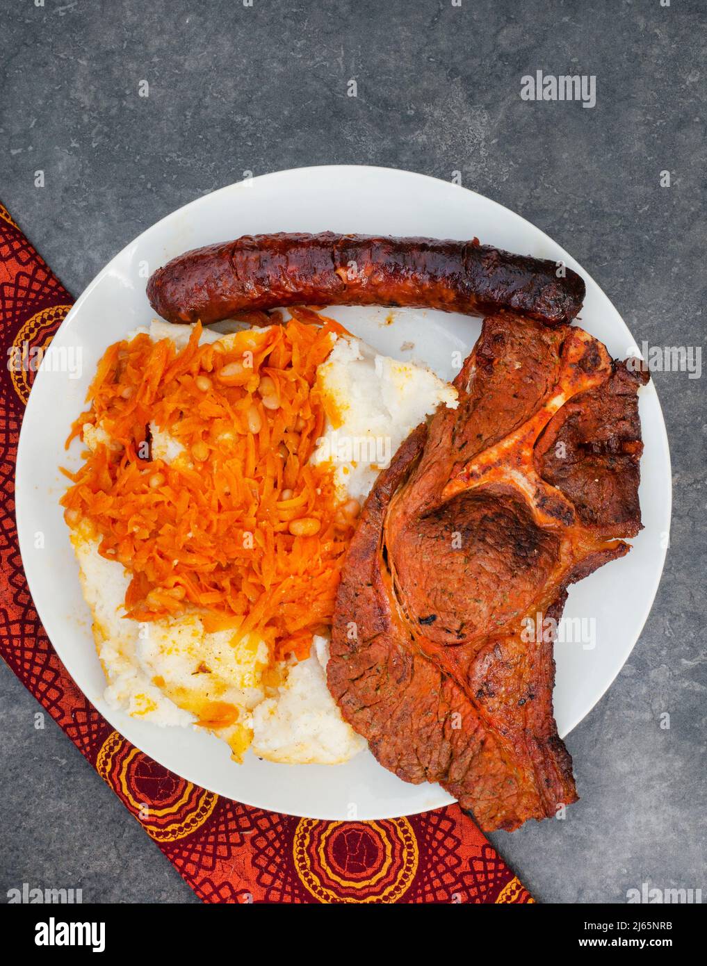 Piatto di Braai tradizionale sudafricano o Shisa nyama, carne cotta a fiamma libera e contorno tradizionale di pap e chakalaka. Foto Stock