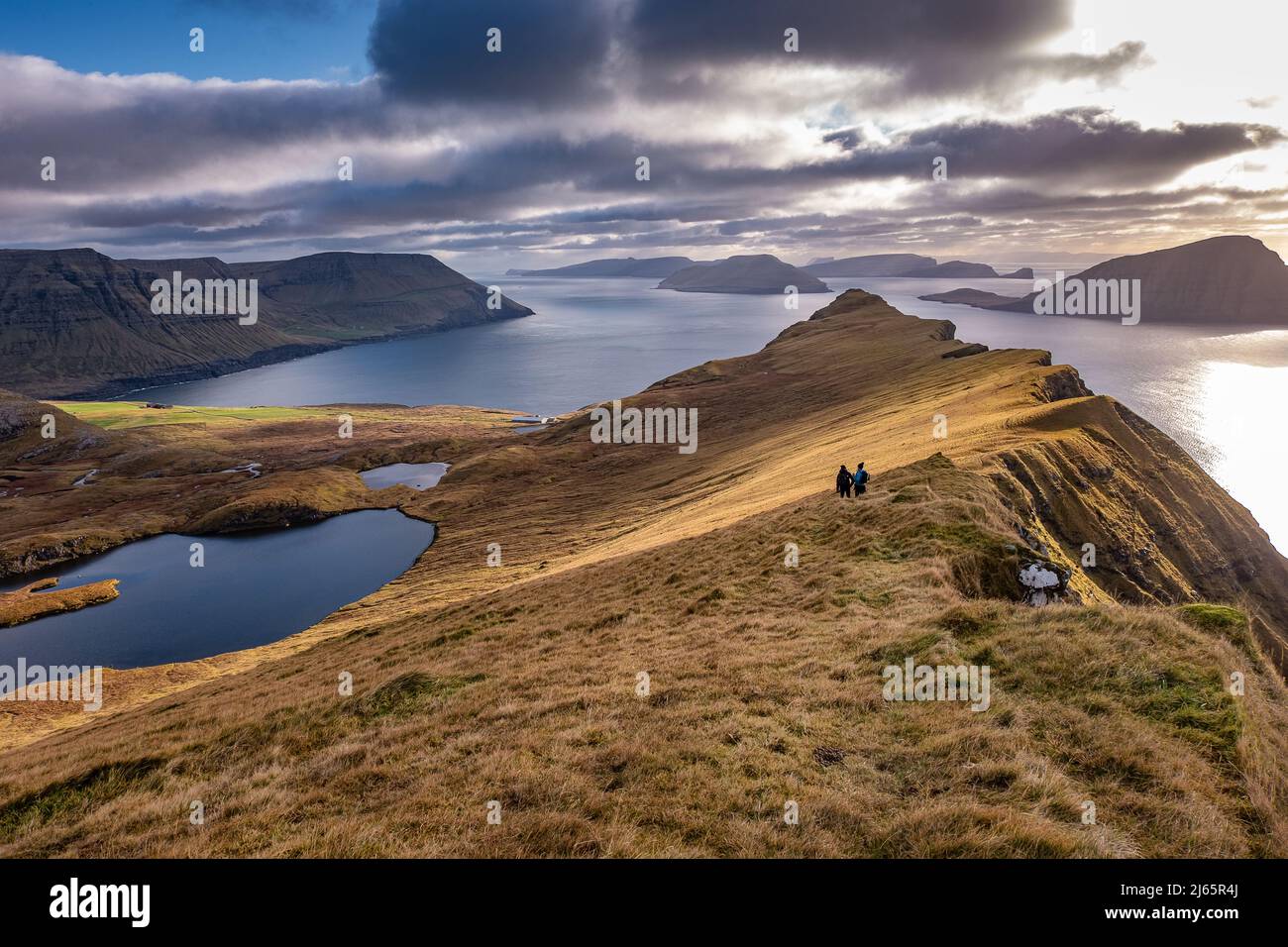 Wandergruppe auf den Färöern,herbstliche Gegenlichtstimmung mit Wolken und Sonne - gruppo escursionistico alle Isole Faroe Foto Stock