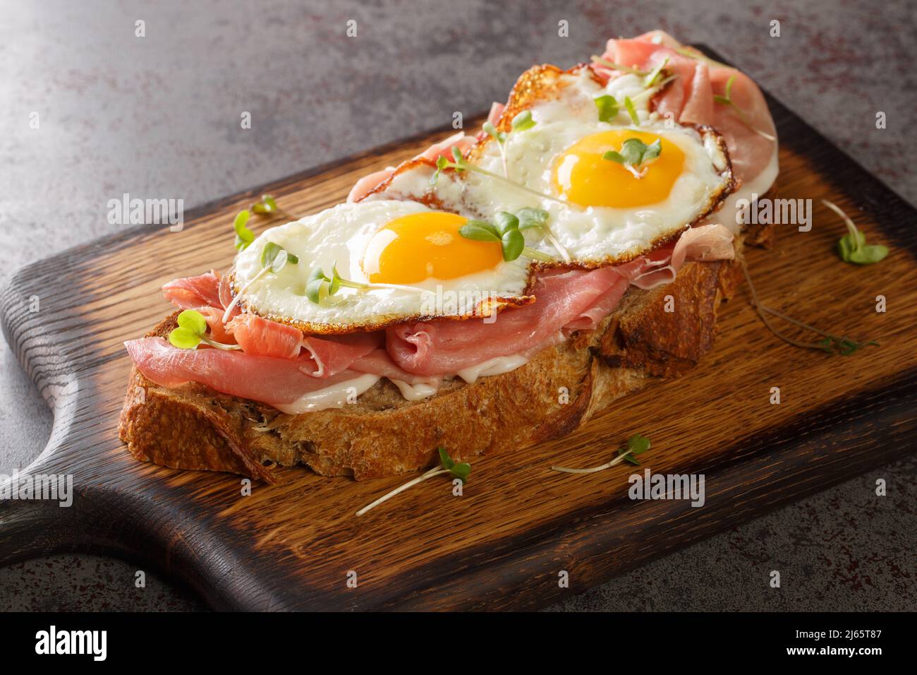 Lo Strammer Max è un panino tedesco a faccia aperta con prosciutto e uova in primo piano sulla tavola di legno sul tavolo. Orizzontale Foto Stock